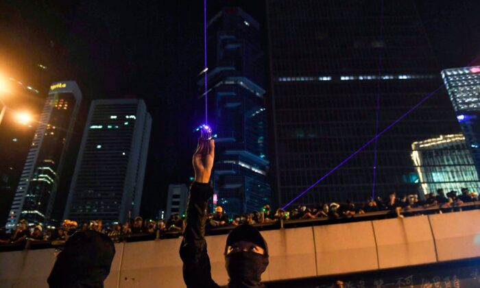 Manifestantes contra el proyecto de ley de extradición apuntan con rayos láser fuera del Consejo Legislativo en Hong Kong el 18 de agosto de 2019. (LILLIAN SUWANRUMPHA/AFP vía Getty Images)