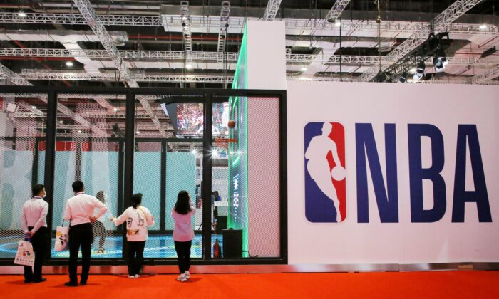 La gente se mantiene junto a un logotipo de la NBA en la Exposición de la NBA en la 3ra Exposición Internacional de Importaciones de China (CIIE) en Shanghai, China, el 5 de noviembre de 2020. (STR/AFP a través de Getty Images)