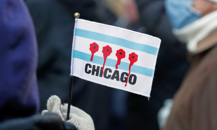 Una mujer sostiene una pequeña bandera con agujeros de bala con sangre durante una marcha contra la violencia armada en la Milla Magnífica de Chicago (Illinois) el 31 de diciembre de 2020. En Chicago, los asesinatos en 2020 hasta el 27 de diciembre ascendieron a 768, lo que supone un aumento de 252 respecto al total de 2019, que fue de 516. (Kamil Krzaczynski/AFP vía Getty Images)