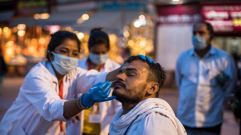 Una trabajadora sanitaria recoge una muestra de hisopo nasal de un devoto hindú para analizar el covid-19 durante el festival religioso Kumbh Mela en curso en Haridwar (India) el 12 de abril de 2021. (Xavier Galiana/AFP vía Getty Images)