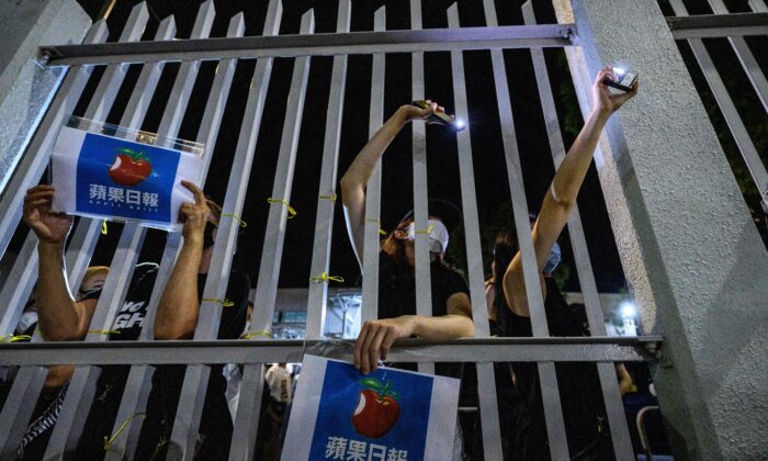 Unos partidarios del Apple Daily se reúnen frente a la puerta principal de las oficinas después de que los últimos periódicos de la compañía se imprimieran en las instalaciones de Hong Kong a primera hora del 24 de junio de 2021. (Anthony Wallace/AFP vía Getty Images)
