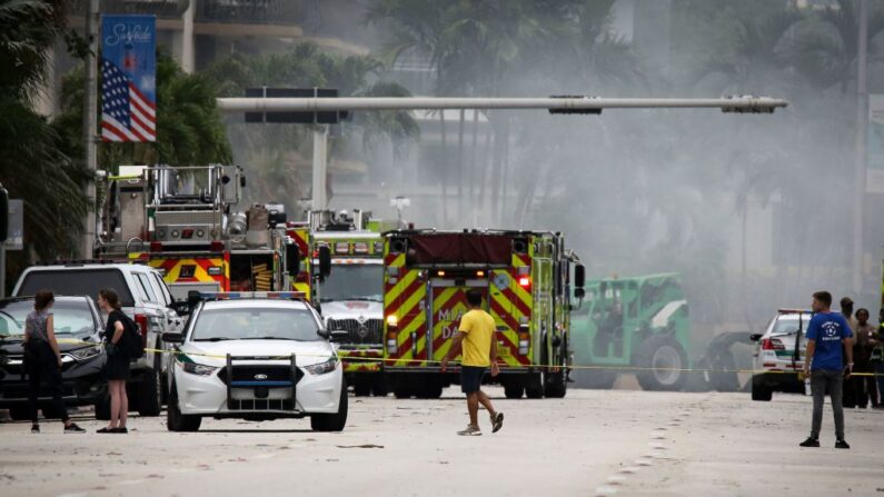 Un hombre camina por Collins Avenue cerca de un edificio parcialmente derrumbado en Surfside, al norte de Miami Beach, el 25 de junio de 2021. (Marco Bello/AFP vía Getty Images)