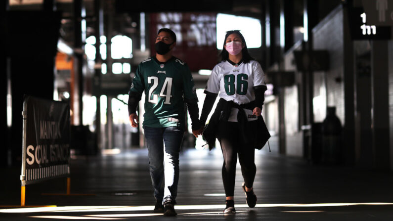 Seguidores de los Philadelphia Eagles usan mascarillas mientras caminan por una explanada vacía el Lincoln Financial Field para un juego contra los Baltimore Ravens, el 18 de octubre de 2020, en Filadelfia, Pensilvania. (Mitchell Leff/Getty Images)