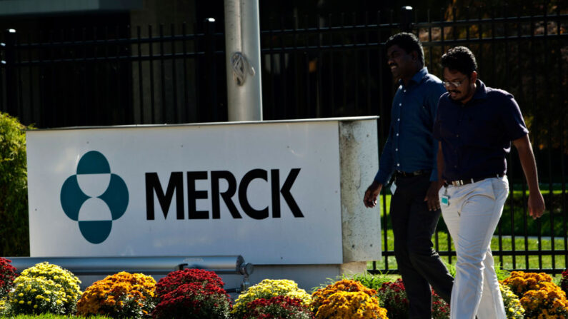 Unos empleados pasan por delante de un cartel de Merck frente al edificio de la compañía el 2 de octubre de 2013 en Summit, Nueva Jersey. (Foto de Kena Betancur/Getty Images)