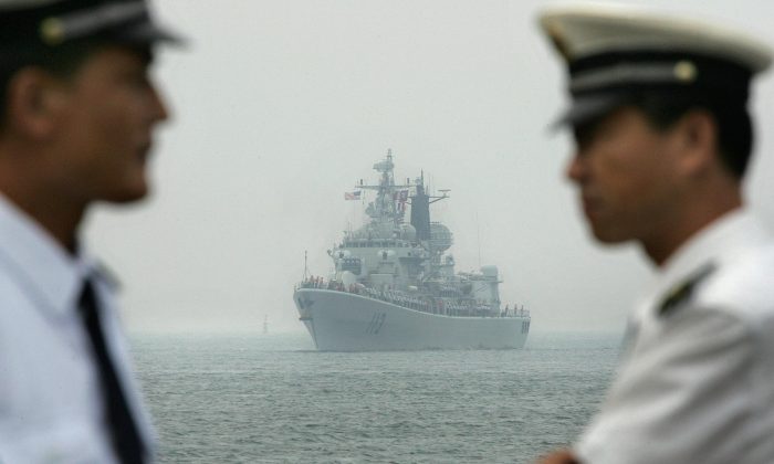 Oficiales de la Armada china esperan en el muelle mientras un buque de guerra de la Armada china escolta la llegada del USS Curtis Wilbur (DDG54), un destructor de misiles guiados clase AEGIS de la Armada estadounidense, que llega al puerto de Qingdao, en la provincia de Shandong, China, el 13 de septiembre de 2005. (FREDERIC J. BROWN/AFP/Getty Images)