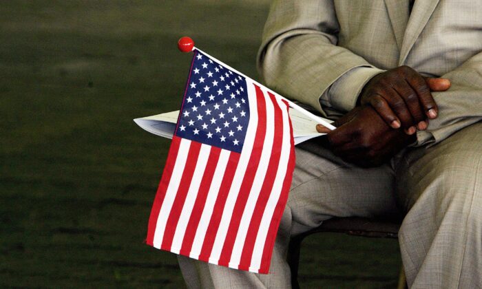 Jeneba Kanu, originaria de Sierra Leona, sostiene una bandera de EE.UU. mientras espera convertirse en ciudadana estadounidense, durante una ceremonia de naturalización en Alexandria, Virginia, el 22 de mayo de 2006. (Jim Watson/AFP a través de Getty Images)