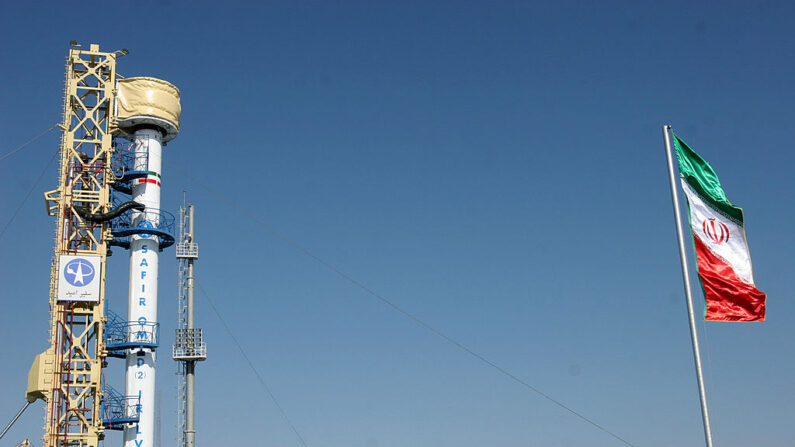 En una foto de archivo, banderas iraníes ondean (d) mientras un cohete de tipo Safir, construido por Irán y diseñado para poner en órbita un satélite, se encuentra en una plataforma de lanzamiento en un lugar no revelado de la república islámica el 2 de febrero de 2009. (AFP vía Getty Images)