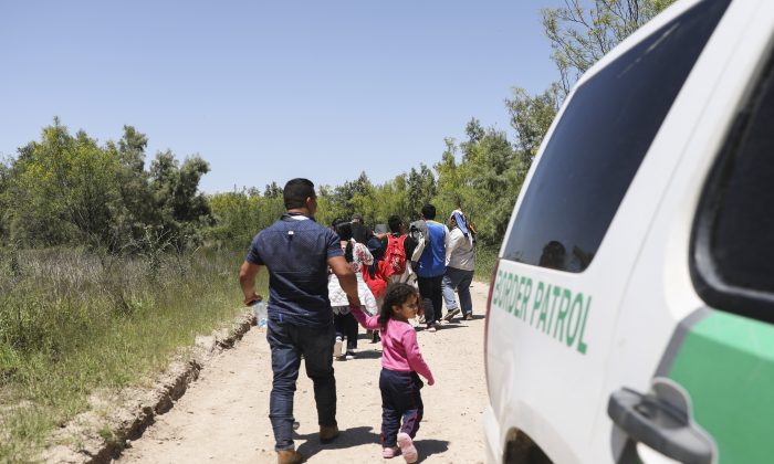 Un grupo de inmigrantes ilegales camina por la carretera después de cruzar el Río Grande desde México. Más adelante, abordarán un autobús con destino a las instalaciones de procesamiento de la Patrulla Fronteriza en McAllen, Texas, el 18 de abril de 2019. (Charlotte Cuthbertson/The Epoch Times)