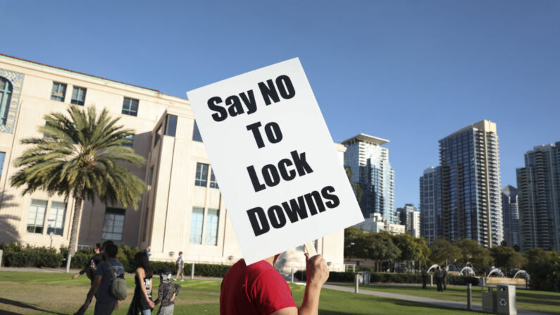 Un hombre sostiene un letrero que se opone al confinamiento durante una manifestación en el Edificio de Administración del Condado, en San Diego, California, el 16 de noviembre de 2020. (Sandy Huffaker/Getty Images)
