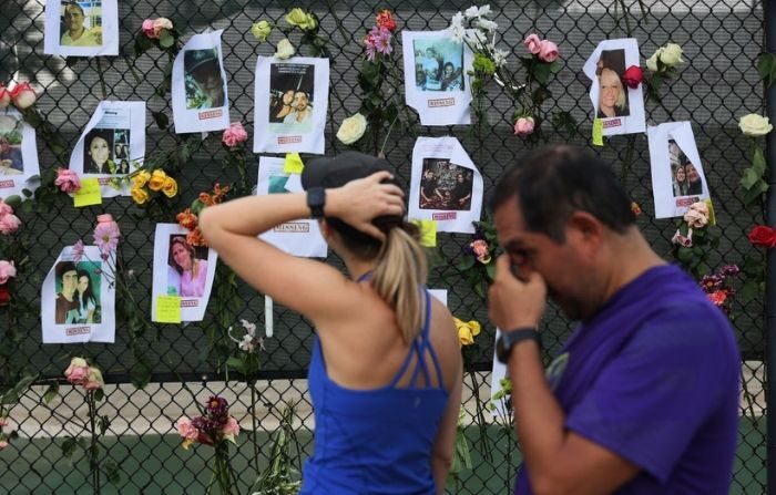 Las personas observan las fotos de algunos de los desaparecidos del edificio de condominios Champlain Towers South, que se derrumbó parcialmente, el 26 de junio de 2021 en Surfside, Florida. (Joe Raedle/Getty Images)