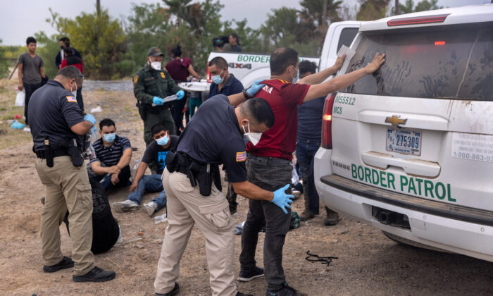 Un oficial de transporte registra a los inmigrantes antes de llevarlos en autobús a un centro de procesamiento después de que cruzaran la frontera desde México en La Joya, Texas, el 13 de abril de 2021. (John Moore/Getty Images)