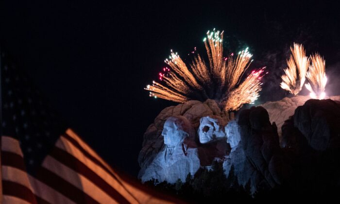 Una bandera de EE.UU. ondea mientras los fuegos artificiales iluminan el área del Monumento Nacional del Monte Rushmore, durante un evento del Día de Independencia, en Keystone, Dakota del Sur, el 3 de julio de 2020. (Andrew Caballero-Reynolds/AFP a través de Getty Images)