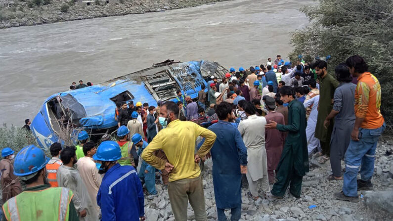 Los trabajadores de rescate y los espectadores se reúnen alrededor de los restos de un autobús que se precipitó por un barranco tras la explosión de una bomba en el distrito de Kohistan de la provincia de Khyber Pakhtunkhwa (Pakistán) el 14 de julio de 2021. (Stringer/AFP vía Getty Images)