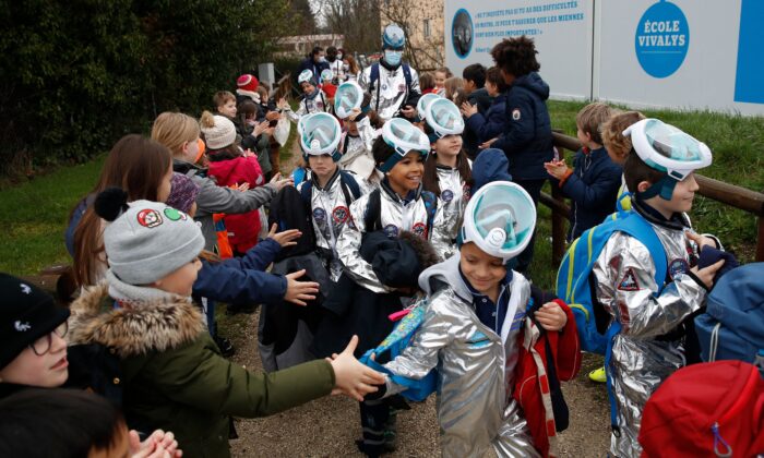 Unos niños dan la mano a los alumnos de la escuela primaria Ecole Vivalys, vestidos con trajes espaciales, al salir de la escuela durante su proyecto Misión a Marte en Lausana, Suiza, el 17 de marzo de 2021. (Stefan Wermuth/AFP vía Getty Images)