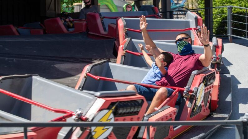 Visitantes con mascarillas disfrutan de la atracción Flash Speed Force en el parque temático Six Flags Magic Mountain el día de la reapertura del parque, el 1 de abril de 2021, en Valencia, California. (Foto de VALERIE MACON/AFP a través de Getty Images)