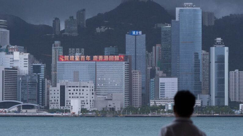 Un hombre mira un edificio con una valla publicitaria LED que muestra un eslogan que celebra el 100º aniversario del Partido Comunista Chino y el 24º aniversario de la devolución de Hong Kong a China en Hong Kong, el 29 de junio de 2021. (Bertha Wang/AFP vía Getty Images)