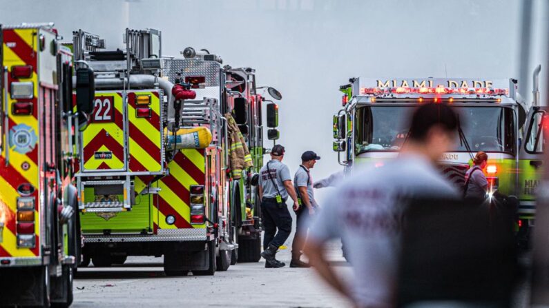 Oficiales de rescate de los bomberos de Miami-Dade junto a los camiones de emergencia mientras los equipos de búsqueda y rescate buscan entre los escombros del edificio de condominios Champlain Towers South, de 12 pisos, parcialmente colapsado, en Surfside, Florida, el 2 de julio de 2021. (Giorgio Viera/AFP vía Getty Images)