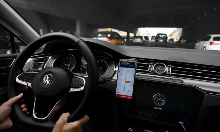 Un conductor usa el mapa en la app DiDi Chuxing de transporte compartido en su teléfono inteligente mientras conduce por una calle en Beijing el 5 de julio de 2021. (GREG BAKER/AFP a través de Getty Images)