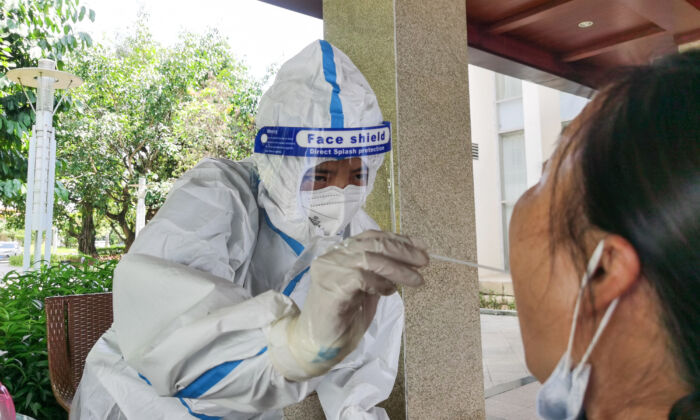 El 8 de julio de 2021, el 8 de julio de 2021, el 8 de julio de 2021, una mujer (derecha) fue sometida a una prueba de ácido nucleico para detectar el virus del PCC en un hotel de la ciudad de Ruili, en la provincia de Yunnan, en el suroeste de China. (STR/AFP a través de Getty Images)