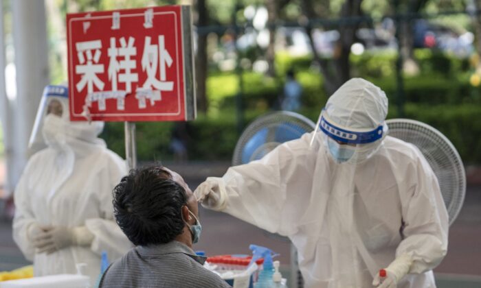 Un hombre (izq.) recibe una prueba de ácido nucleico para Covid-19 en Mangshi, en la prefectura autónoma de Dehong Dai y Jingpo, que limita con Myanmar, en la provincia de Yunnan, suroeste de China, el 9 de julio de 2021. (STR/AFP a través de Getty Images)