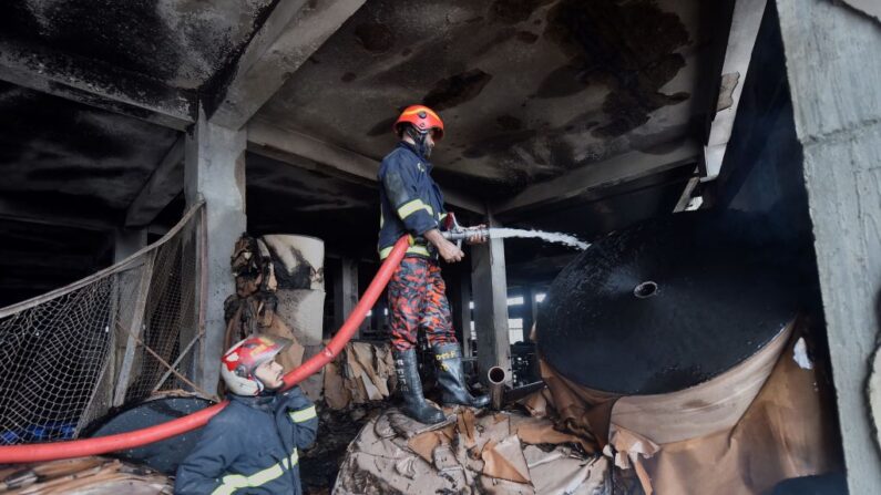 Los bomberos extinguen un incendio en la planta baja de la fábrica quemada después de haber conseguido apagar el fuego en Rupganj (Bangladesh) el 10 de julio de 2021. (Munir Uz zaman/AFP vía Getty Images)