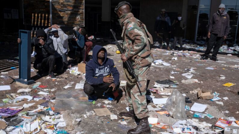 Un presunto saqueador suplica a un soldado de la Fuerza de Defensa Nacional de Sudáfrica (SANDF) que detiene a presuntos saqueadores en el centro comercial Jabulani en Soweto, en las afueras de Johannesburgo (Sudáfrica), el 13 de julio de 2021. (Emmanuel Croset/AFP vía Getty Images)