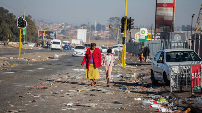  Una mujer y una niña caminan entre los escombros el 14 de julio de 2021 en Vosloorus, Johannesburgo, Sudáfrica. (James Oatway/Getty Images)
