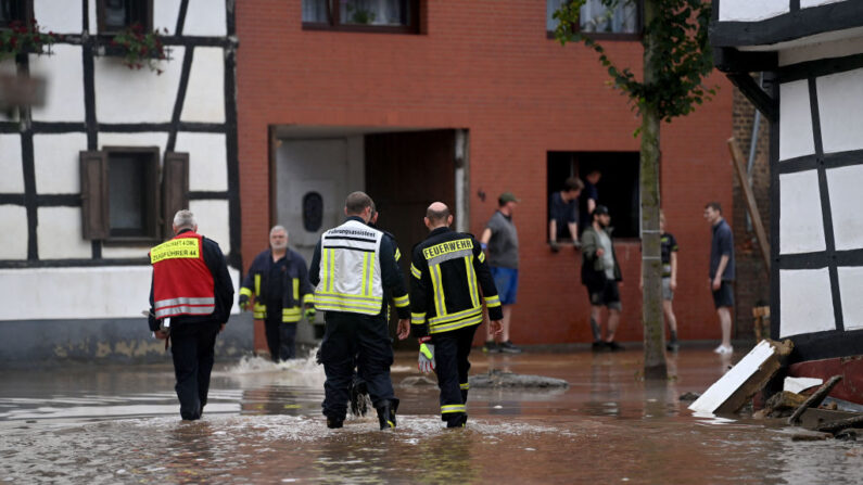 Los bomberos vadean el agua frente a las casas inundadas en Iversheim, cerca de Bad Muenstereifel, en el oeste de Alemania, el 16 de julio de 2021, tras las fuertes lluvias e inundaciones. (Ina Fassbender/AFP vía Getty Images)