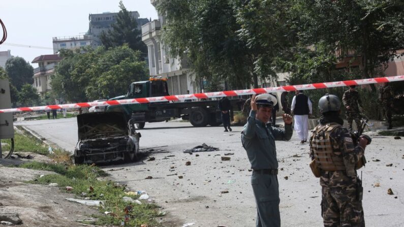 Personal de seguridad afgano monta guardia cerca de un vehículo carbonizado desde el que se dispararon cohetes que cayeron cerca del palacio presidencial afgano en Kabul el 20 de julio de 2021. (AFP vía Getty Images)