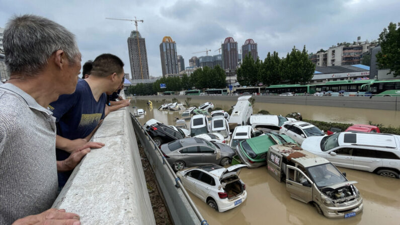 La gente mira los autos estancados en las aguas tras una inundación después de que fuertes lluvias golpearan la ciudad de Zhengzhou, provincia de Henan, China, el 21 de julio de 2021. (STR/AFP vía Getty Images)