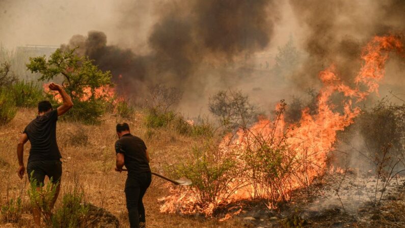 Unas personas apagan unos arbustos en llamas durante un incendio forestal masivo que arrasó una región turística del Mediterráneo en la costa sur de Turquía, cerca de la ciudad de Manavgat, el 29 de julio de 2021. (Ilyas Akengin/AFP vía Getty Images)