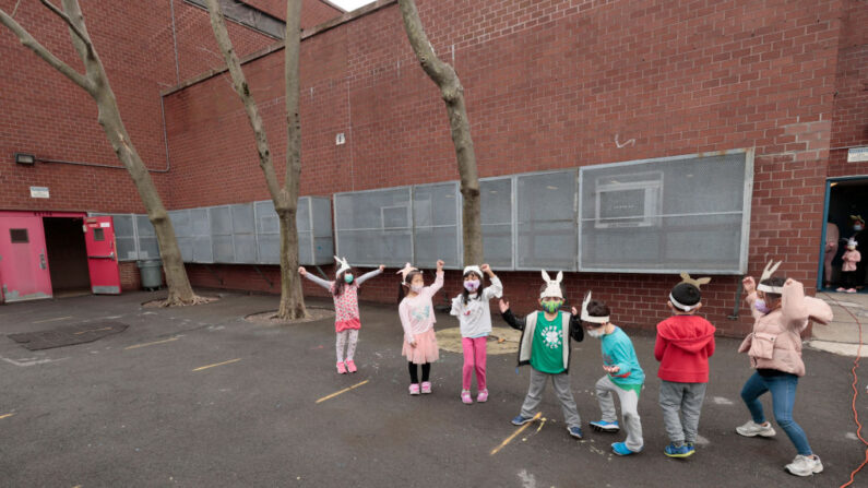 Los niños hacen fila para volver a sus aulas después de participar en un salto de conejo y un retrato de clase en el patio de la escuela Yung Wing P.S. 124 el 25 de marzo de 2021 en la ciudad de Nueva York. (Michael Loccisano/Getty Images)