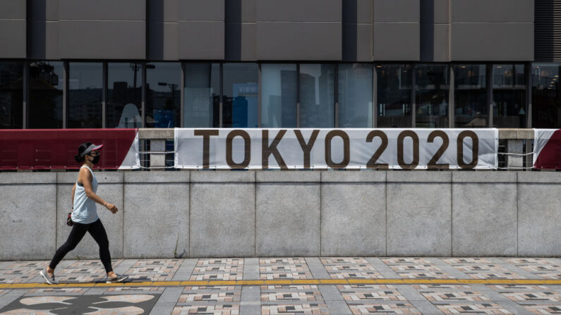 Una mujer con una mascarilla pasa por delante de una pancarta de Tokio 2020 el 12 de julio de 2021 en Tokio, Japón. (Takashi Aoyama/Getty Images)
