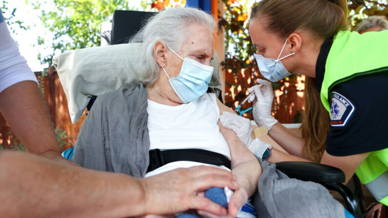 La paramédico Barbara Pople administra una dosis de vacuna COVID-19 a Marilyn Lurie, que está confinada en casa y sufre demencia frontotemporal, en el patio trasero de la casa de Lurie el 16 de julio de 2021 en Los Ángeles, California. (Mario Tama/Getty Images)
