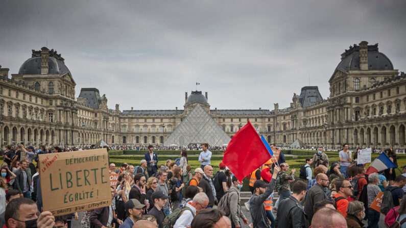 Manifestantes antivacunas marchan frente al Museo del Louvre mientras miles de personas salen a las calles de la capital francesa para protestar contra el nuevo pase de la vacuna COVID-19 anunciado por el presidente Macron, el 17 de julio de 2021 en París, Francia.(Kiran Ridley/Getty Images)