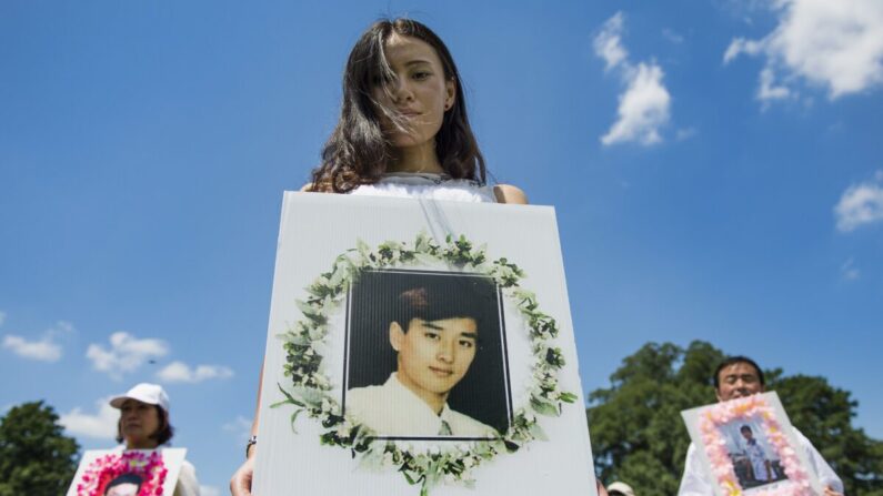 Practicantes de Falun Gong sostienen fotografías conmemorativas mientras marchan en el Capitolio en Washington, el 17 de julio de 2014. (Jim Watson/AFP a través de Getty Images)