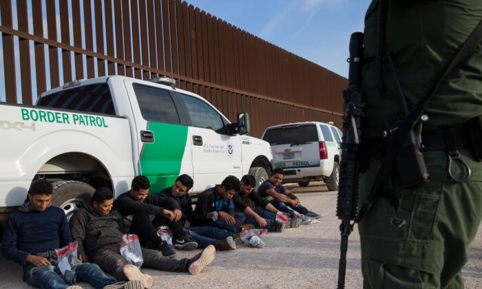 Después de ser detenidos por la Patrulla Fronteriza, los inmigrantes ilegales esperan ser transportados a un centro de procesamiento central poco después de cruzar la frontera de México a Estados Unidos en el sector del Valle del Río Grande cerca de McAllen, Texas, el 26 de marzo de 2018. (Loren Elliott/AFP vía Getty Images)