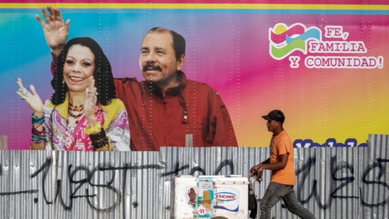 Un vendedor de helados camina junto a una clínica de salud móvil que muestra una imagen del presidente de Nicaragua Daniel Ortega (I) y su esposa la vicepresidenta Rosario Murillo (D) en Managua (Nicaragua) el 14 de abril de 2020. (Inti Ocon/AFP vía Getty Images)