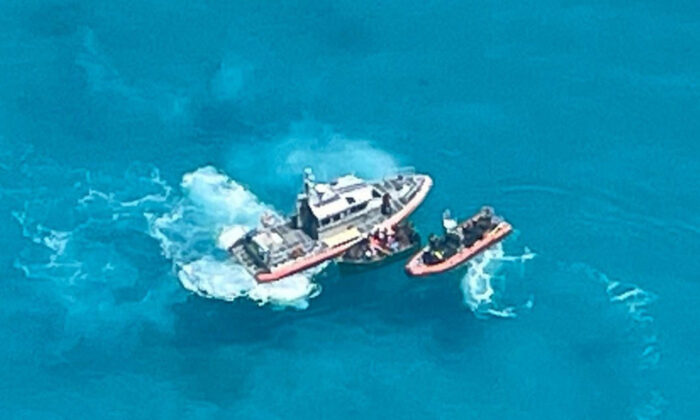 La escena muestra a la tripulación de la Estación de la Guardia Costera de Key West junto a una embarcación de 21 pies con 22 personas a bordo aproximadamente a 7 millas al sur de Key West, Florida, el 23 de julio de 2021. (U.S. Coast Guard Auxiliary)