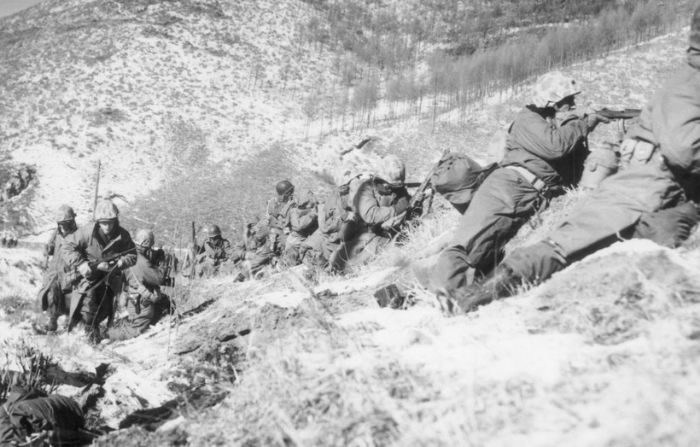 Los soldados de infantería de la Infantería de Marina de los Estados Unidos, cubriéndose detrás de grandes rocas, disparan a las fuerzas norcoreanas durante una batalla en una montaña cubierta de nieve en la Guerra de Corea, el 6 de diciembre de 1950. Los marines ganaron la batalla, respaldados por un apoyo aéreo cercano. (Archivo Hulton/Getty Images)