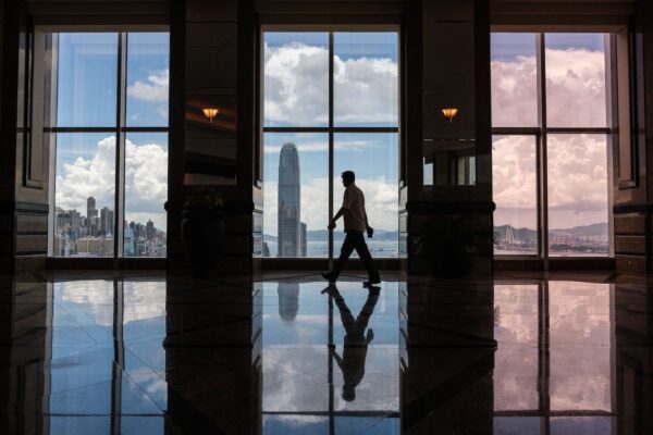 Un hombre camina frente a las ventanas que muestran una vista del horizonte de Hong Kong, el 21 de julio de 2020. (Anthony Wallace/AFP a través de Getty Images)