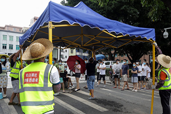 Los voluntarios instalan una tienda de campaña mientras los residentes se preparan para recibir las pruebas de ácido nucleico por el COVID-19 en Guangzhou, en la provincia meridional china de Guangdong, el 30 de mayo de 2021. (STR/AFP vía Getty Images)
