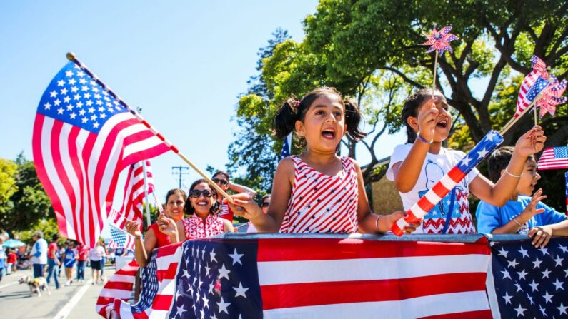 La gente agita banderas estadounidenses mientras recorre el desfile del 4 de julio en Alameda, California, el 4 de julio de 2016. (Gabrielle Lurie/AFP/Getty Images)