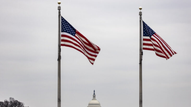 El edificio del Capitolio de Estados Unidos se ve junto a las banderas estadounidenses en la base del Monumento a Washington en Washington el 15 de febrero de 2021. (Samuel Corum/Getty Images)