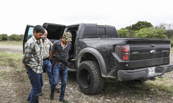 El ayudante del sheriff del condado de Kinney, Chris Coplan, arresta a dos extranjeros ilegales después de que la camioneta robada en la que viajaban pasara a toda velocidad por un puesto de control y entrara en un rancho cerca de Brackettville, Texas, el 16 de agosto de 2021. (Charlotte Cuthbertson/The Epoch Times)