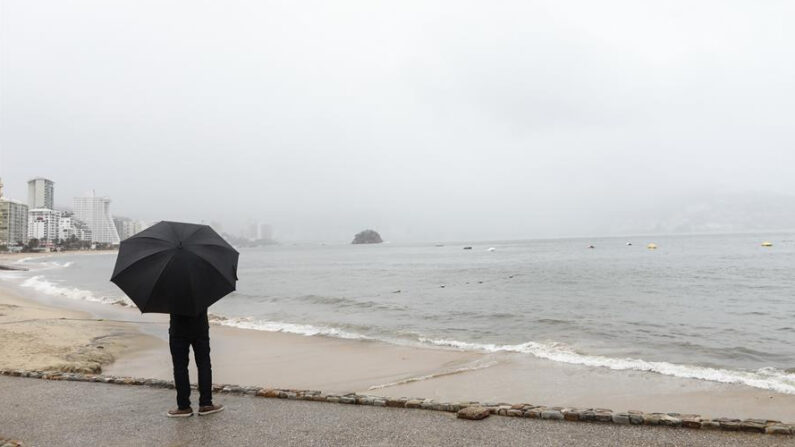 Un hombre con sombrilla mira hacia el océano en Acapulco (México). EFE/ David Guzmán/Archivo
