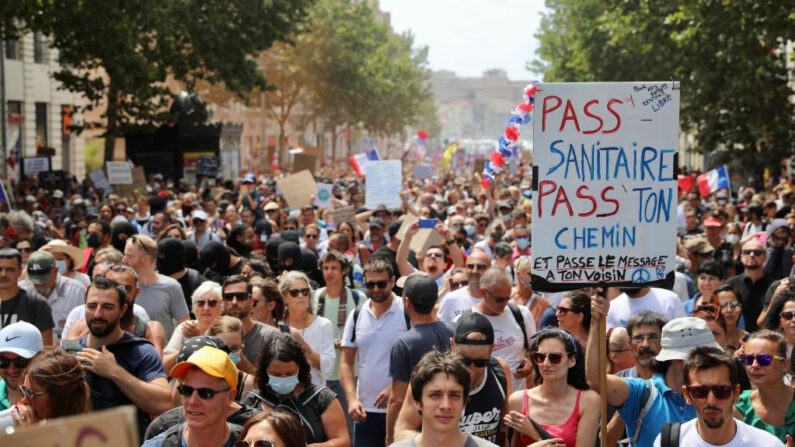Manifestantes sostienen pancartas y carteles durante una protesta nacional contra la tarjeta sanitaria covid-19 de Francia el 7 de agosto de 2021 en Marsella, Francia. (Roger Anis/Getty Images)