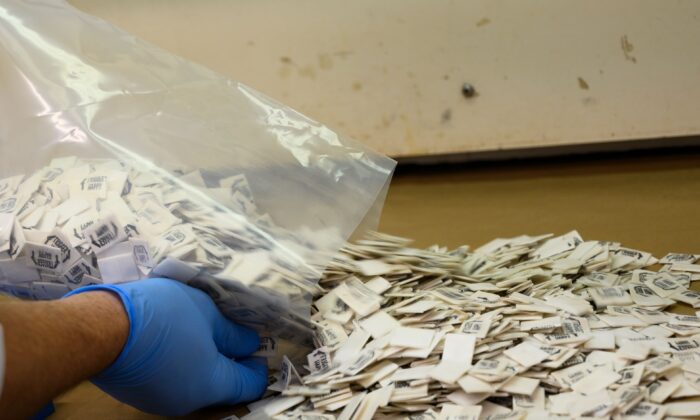 Un químico de la Administración de Control de Drogas (DEA) vierte 2500 paquetes de fentanilo confirmado en un mostrador para su análisis en el Laboratorio Regional del Noreste de la DEA en Nueva York el 8 de octubre de 2019. (Don Emmert/AFP vía Getty Images)
