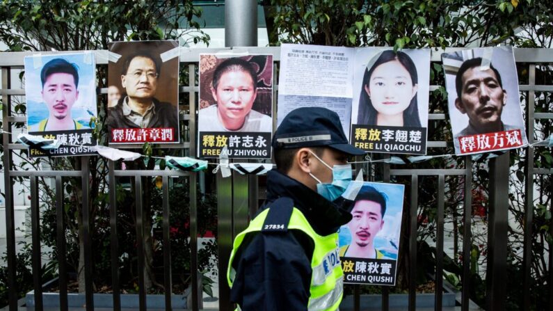 Un oficial de policía pasa junto a carteles de activistas de derechos que fueron detenidos. Los carteles se encuentran pegados en la valla de la oficina de enlace china, en protesta por la detención en Beijing del destacado activista anticorrupción Xu Zhiyong, en Hong Kong, China, el 19 de febrero de 2020. (Isaac Lawrence/AFP a través de Getty Images)