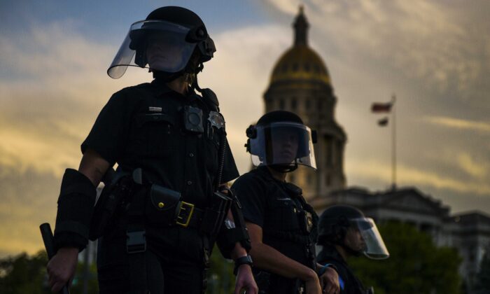 Agentes de policía vigilan a una multitud de personas cerca del capitolio del estado de Colorado durante una protesta en Denver (Colorado) el 29 de mayo de 2020. (Michael Ciaglo/Getty Images)
